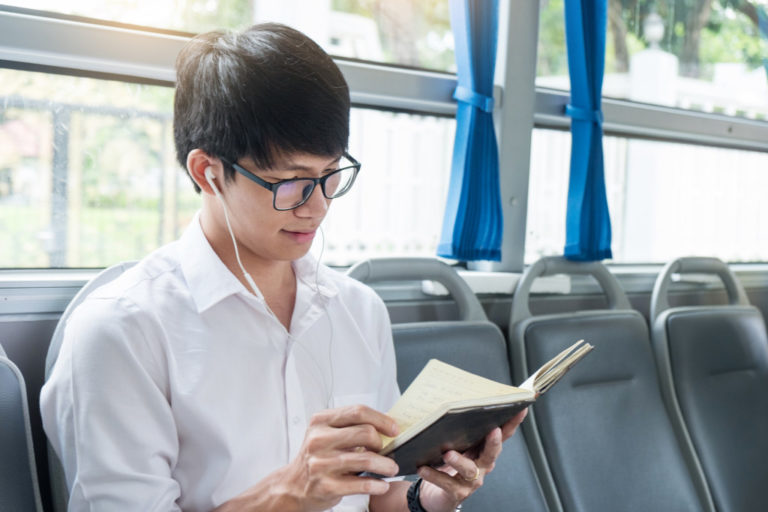 man reading a book in public transportation
